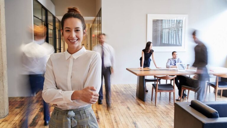 Portrait of young white woman in a busy modern workplace
